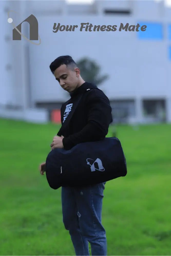 Man holding a black duffel bag with ’Your Fitness Mate’ text visible.