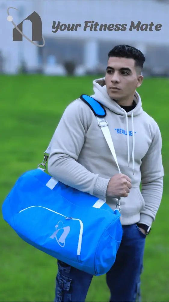 Young man wearing a gray hoodie and carrying a bright blue duffel bag.